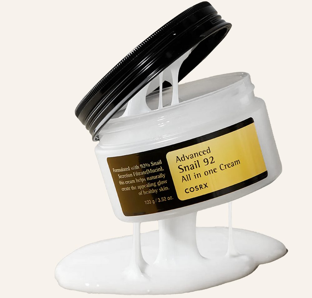 COSRX Advanced Snail 92 cream jar with elastic white cream stretching from the lid