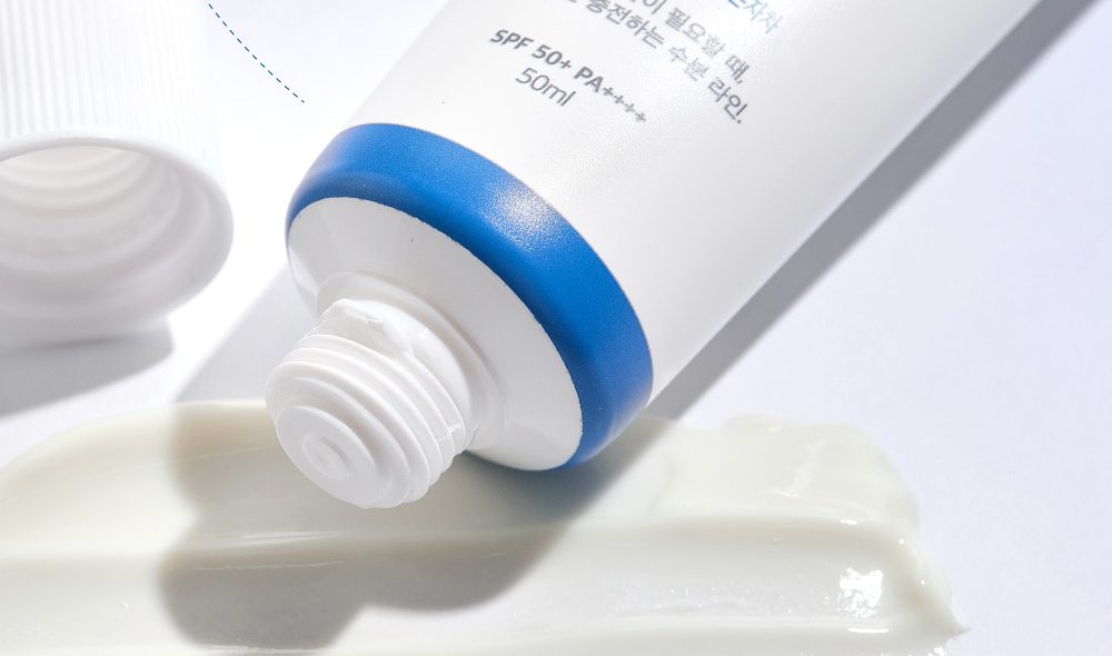 ROUND LAB Birch Juice Moisturizing Sunscreen tube nozzle resting on a spread of white sunscreen cream